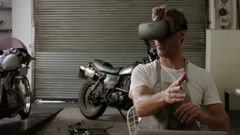 Male-mechanic-using-virtual-reality-headset-in-motorbike-repair-garage-4k