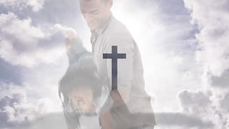 animation of crucifix cross monument and cloudy sky over biracial father playing with son