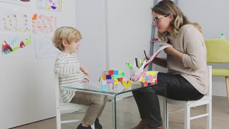 psychologist sitting near boy drawing on paper