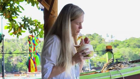 mujer disfrutando del agua de coco en la playa