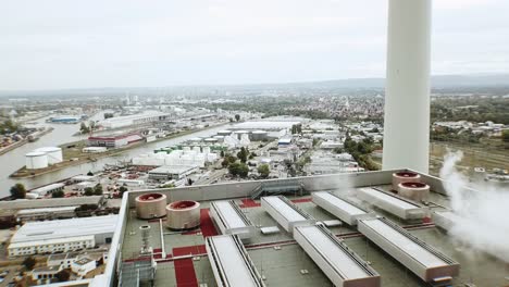 High-altitude-Drone-flight-over-the-roof-of-a-giant-coal-power-plant-building-in-western-Europe-with-smoke-and-overcast-skies