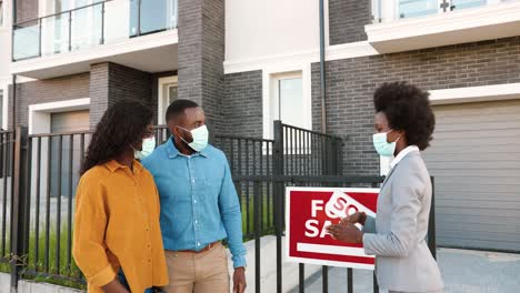 african american young woman real-eastate agent selling house to happy just-married couple