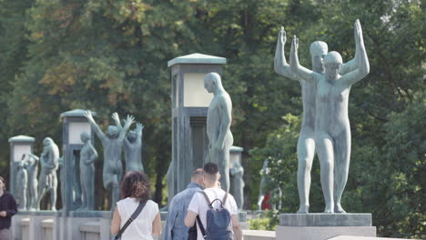 tourists walk along the bridge past sculptures in vigeland park, frogner park