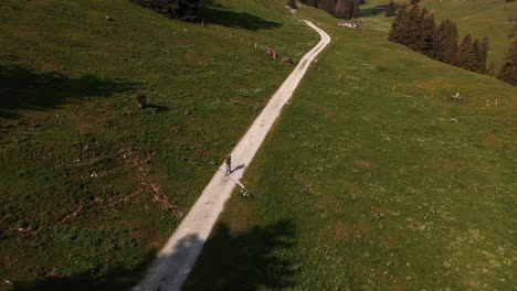 aerial drone shot, backpacker hiking on mountain cliffside dirt trail during summer