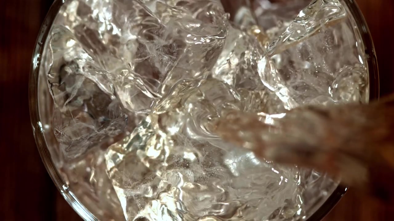 Primo piano dall'alto di acqua che si versa in un bicchiere con ghiaccio
