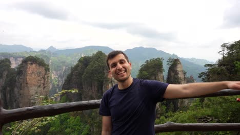 hombre feliz en un punto de vista de la aldea de huangshi disfrutando del paisaje con pilares cársticos y vegetación verde, china