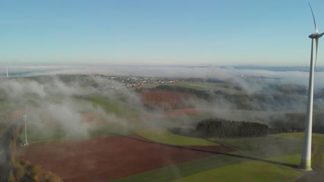 una mañana con niebla en una zona rural de luxemburgo con vistas a un aerogenerador y una carretera