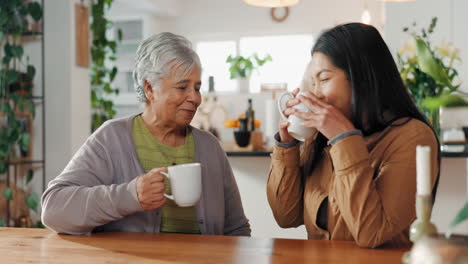 two women, a mother and her daughter, sit at a table together, smiling and drinking coffee. they look at each other and seem to be enjoying their time together.