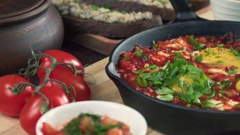 israeli cuisine. sprinkling parsley on shakshuka in pan close-up. national jewish dish made of eggs fried in tomato sauce, hot peppers, onions and spices, middle eastern culture, chakchouka