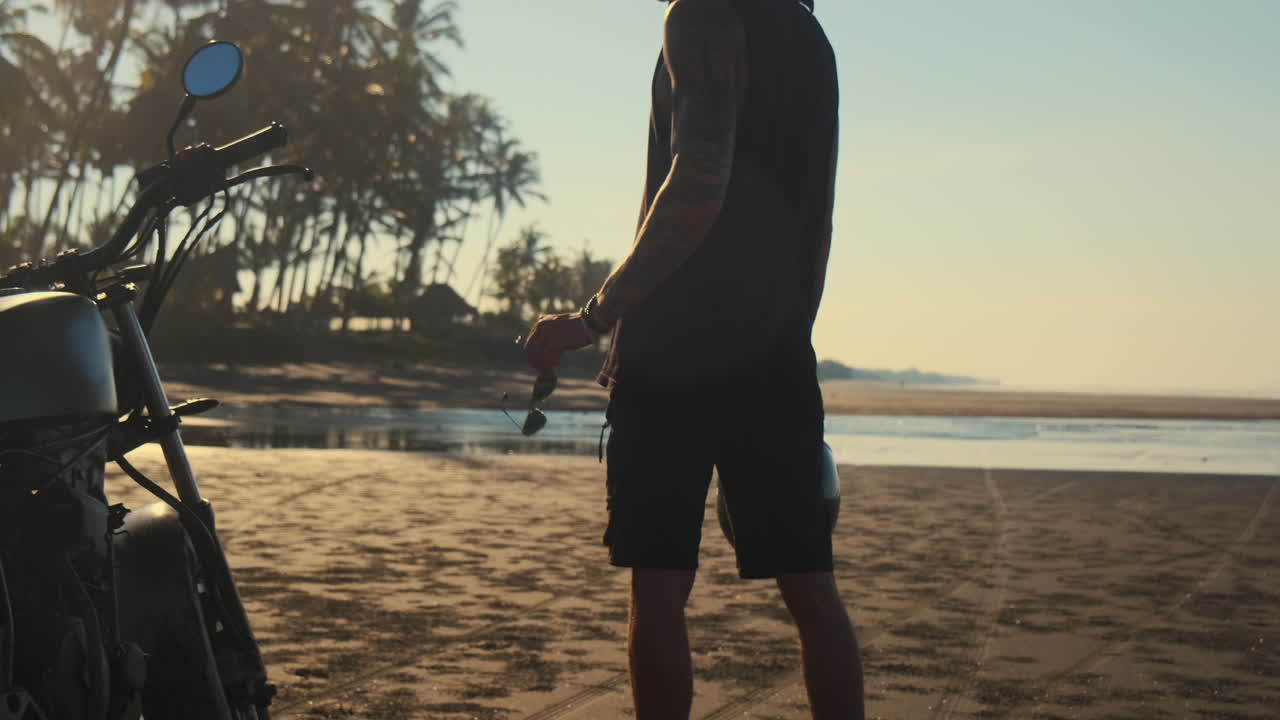 hombre en una motocicleta en la playa al amanecer o al atardecer