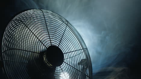 fan blades rotate in rays of light and fog. close-up shot