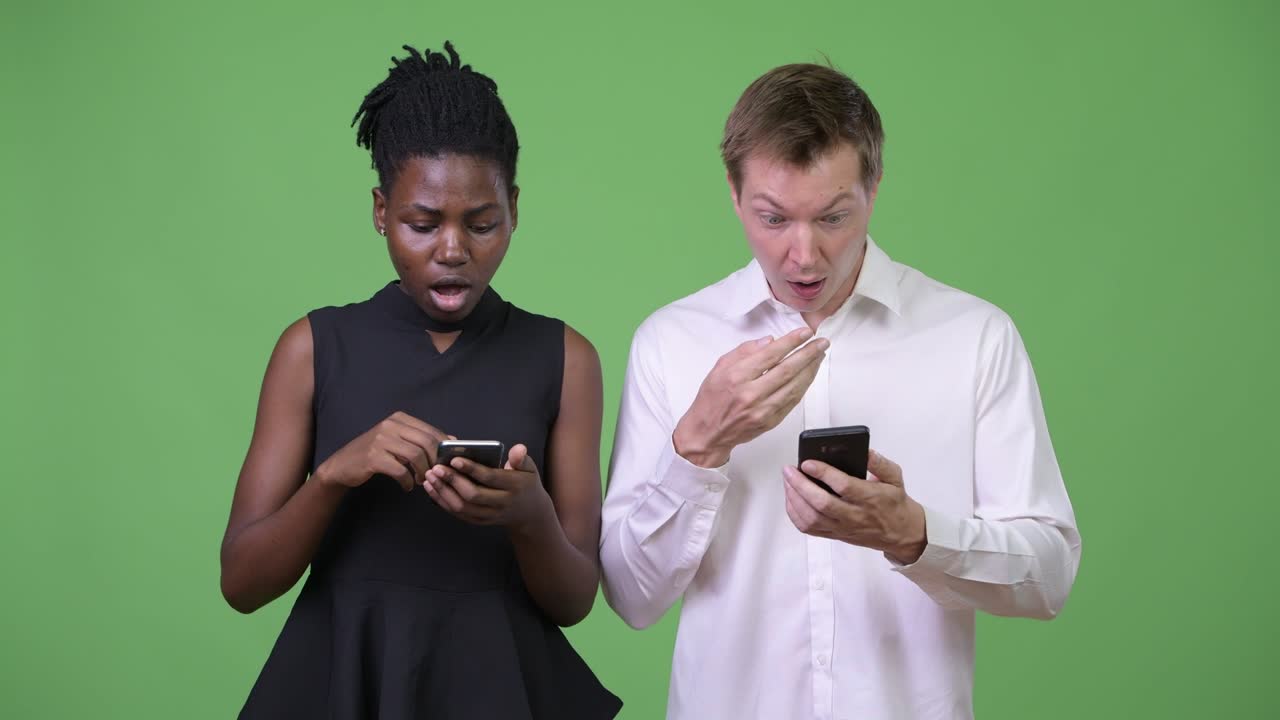 Two young multi-ethnic business couple using phone together