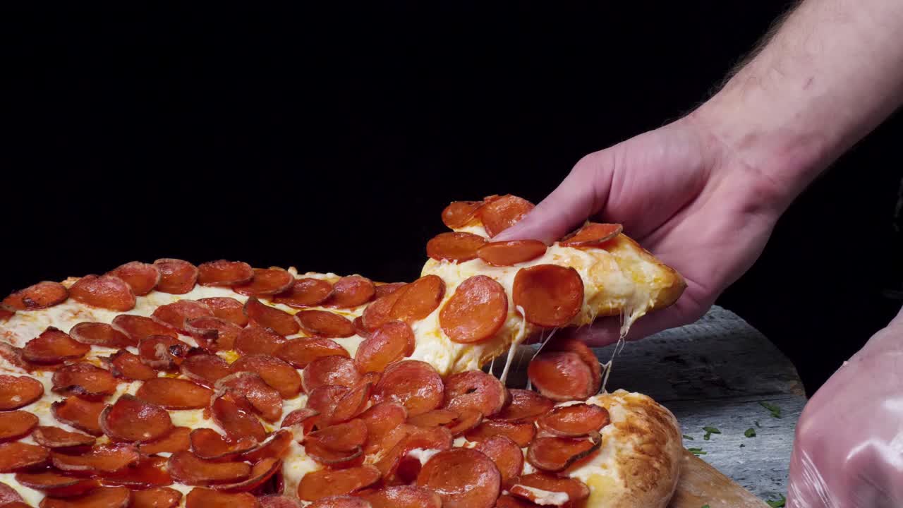 페페로니 피자의 조각을 들고 있는 손