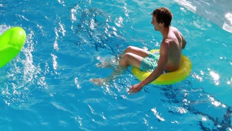 Couple-sitting-on-inflatable-rings-in-the-swimming-pool