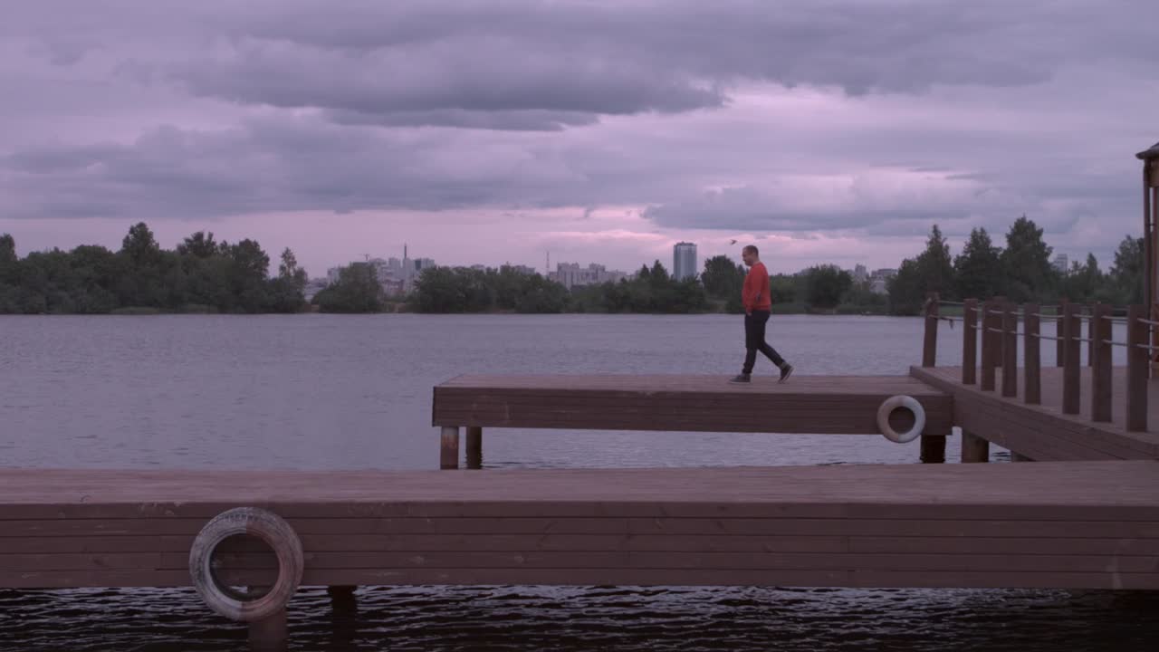 Man walking on a pier by the lake at sunset