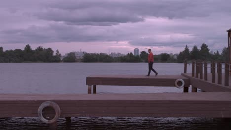 man walking on a pier by the lake at sunset
