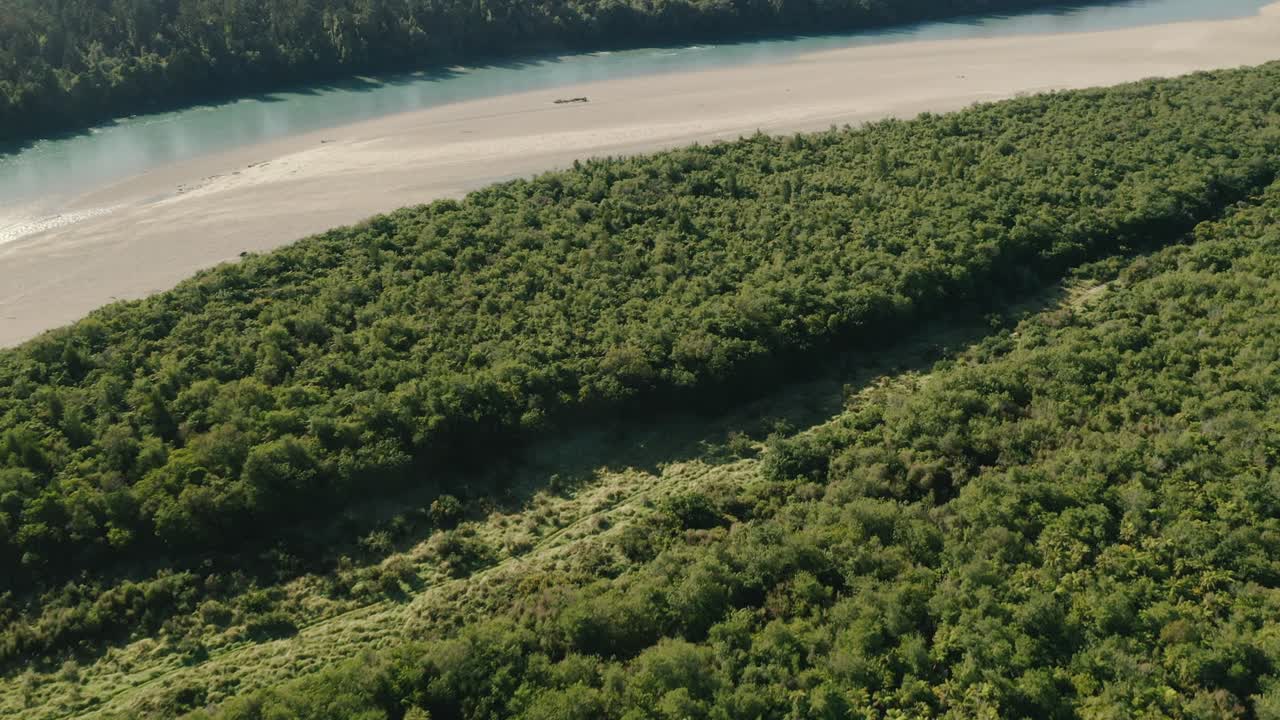 뉴질랜드 서해안 해안에서 바다로 흐르는 강 지류의 공중 틸팅 샷