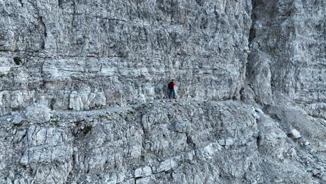 a male person walking along an exposed hiking trail in the dolomites in italy