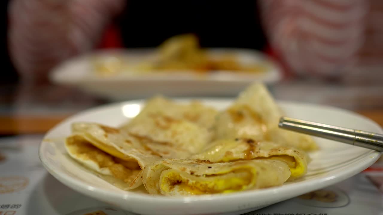 cerca de quiche en el restaurante. con palillos. el fondo borroso es una niña tomando una comida.