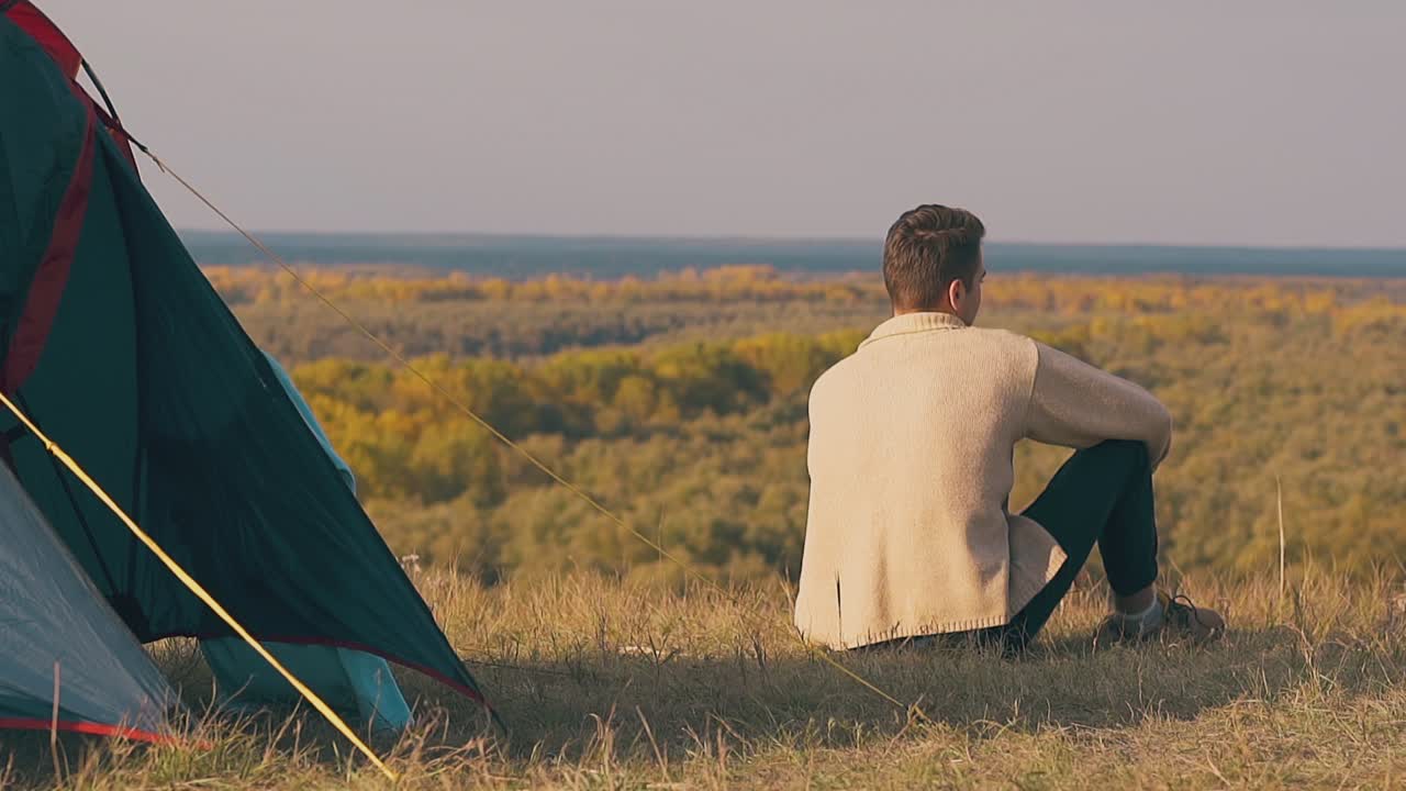 외로운 남자가 파란 텐트 그림자  ⁇ 에 앉아 숲을 존경합니다.