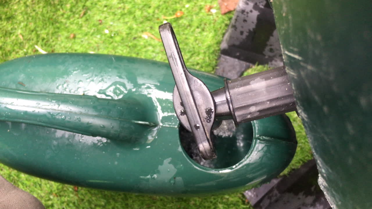 Looking down on a watering can being filled up from a water butt