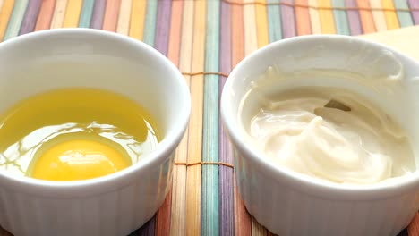 mayonnaise in container , oil and eggs on table ,