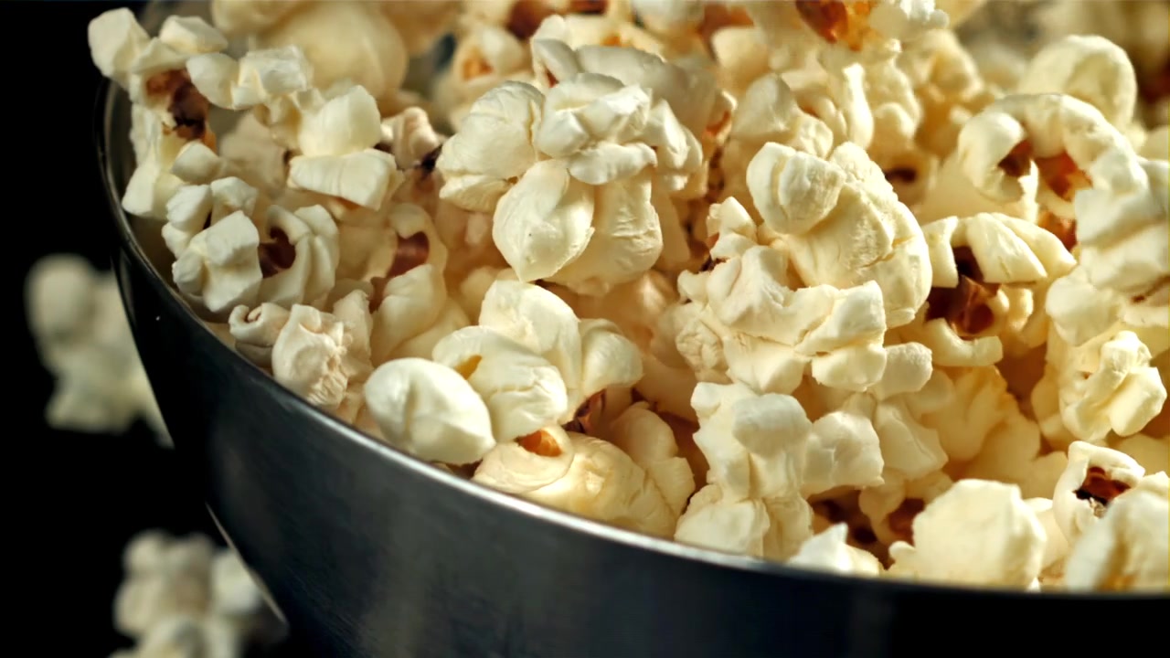 Popcorn che cadono al rallentatore in una ciotola metallica.