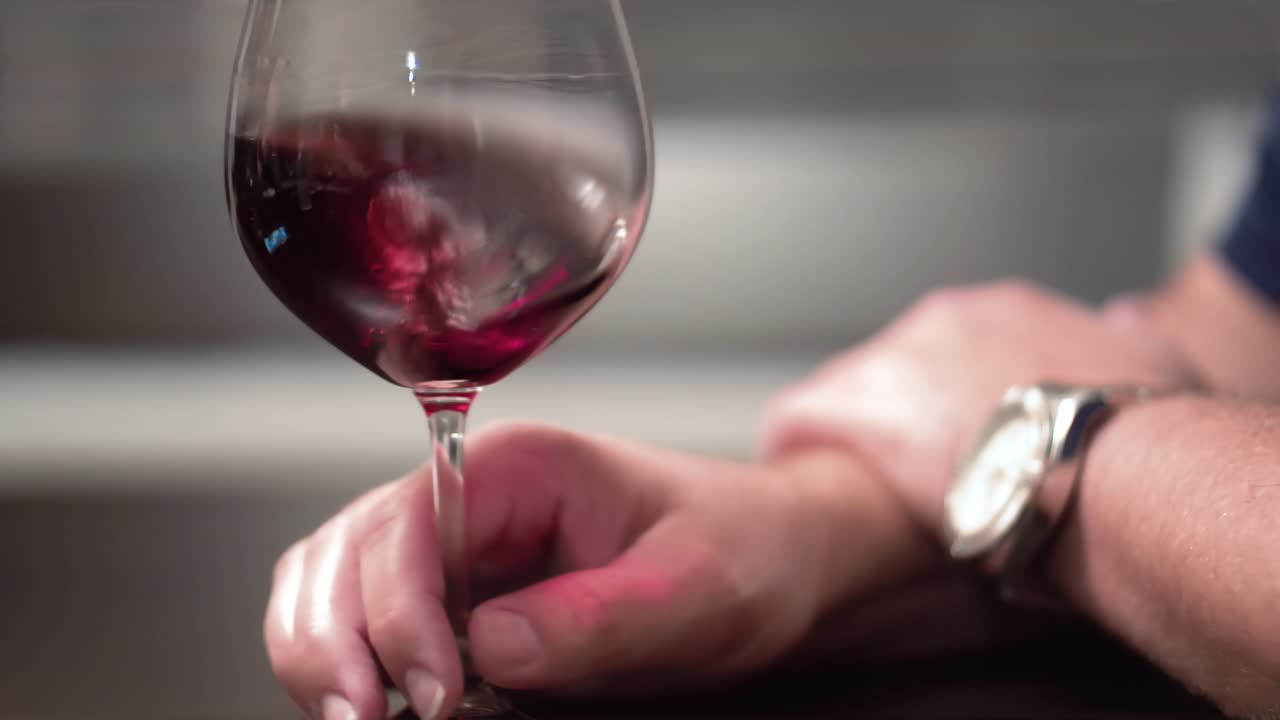 Mano maschile che aera un bicchiere di vino rosso.