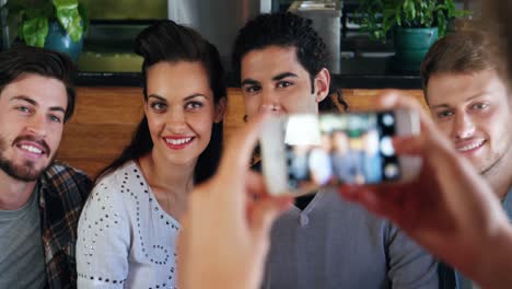 mujer haciendo clic en la foto de amigos en el teléfono móvil