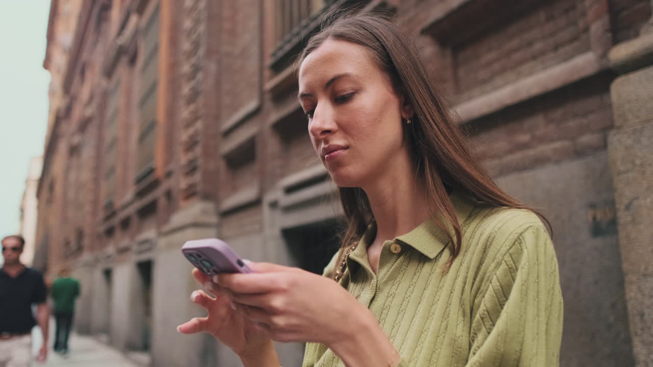 Giovane donna che cammina e usa lo smartphone su una strada cittadina