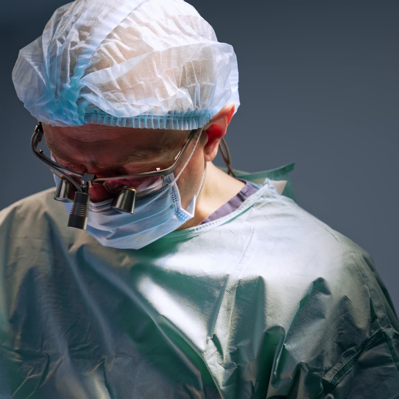 Chirurgo adulto di sesso maschile in uniforme che indossa mascherina, cuffia e occhiali. Ritratto di un medico professionista impegnato in un'operazione