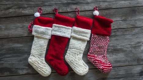 four knitted christmas stockings on wooden background