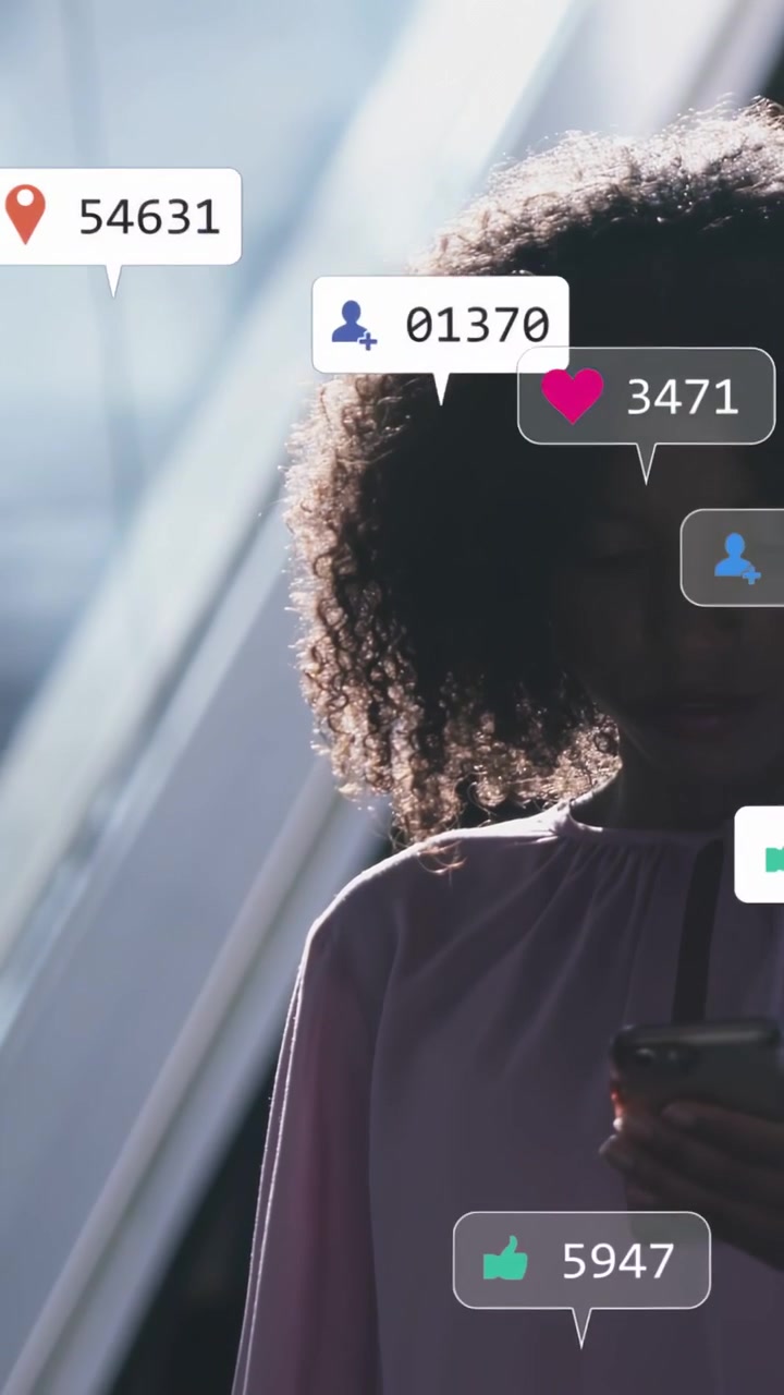 Vertical video: Woman tapping phone in atrium checking social media icons growing near phone