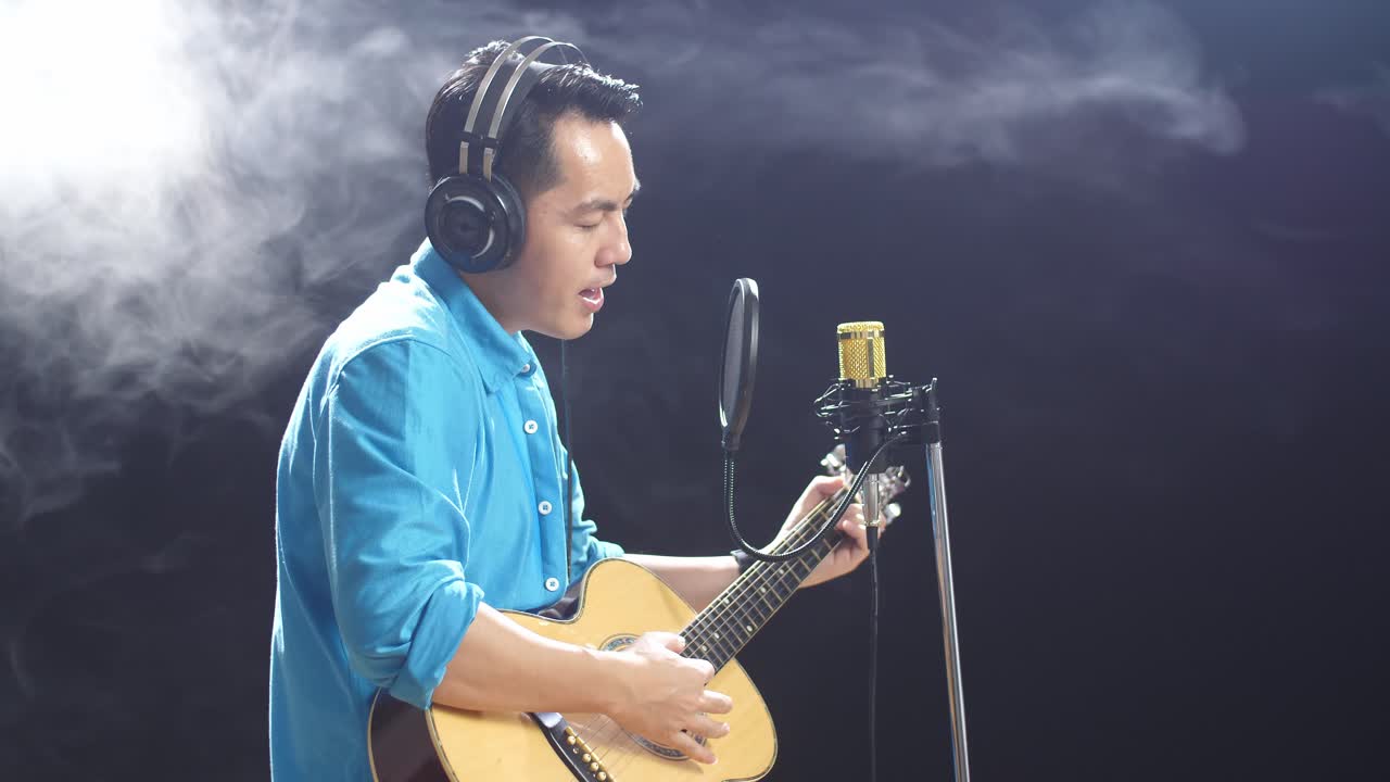 녹음 스튜디오 에서 노래 하고 어쿠스틱 기타 를 연주 하는 남자