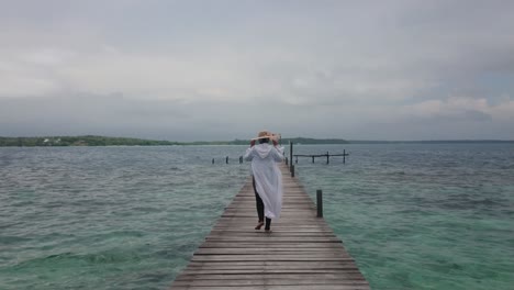 Woman-tourist-in-summer-hat-walking-on-the-wooden-dock-at-the-sea