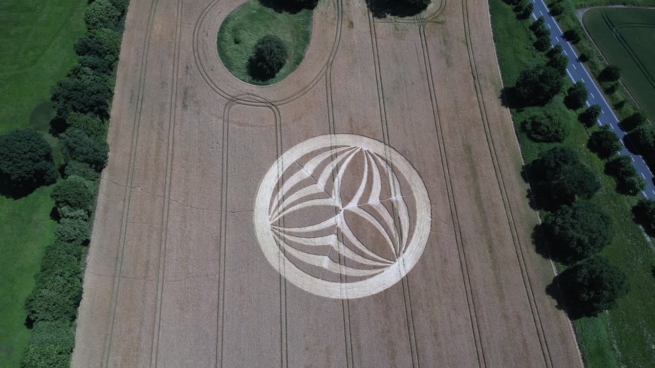 Descending aerial view above Warminster crop circle 2023, mysterious symmetrical alien pattern on harvested corn field in England