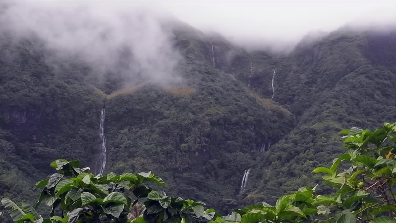 Pan across low cloud jungle mountain waterfalls in French Polynesia