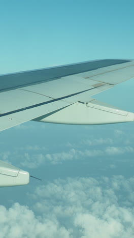 view from a plane window of the sky with the wing of the plane in shot in vertical