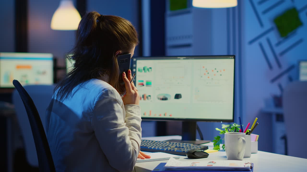 freelancer cansado hablando en teléfono inteligente con un colega que trabaja horas extras