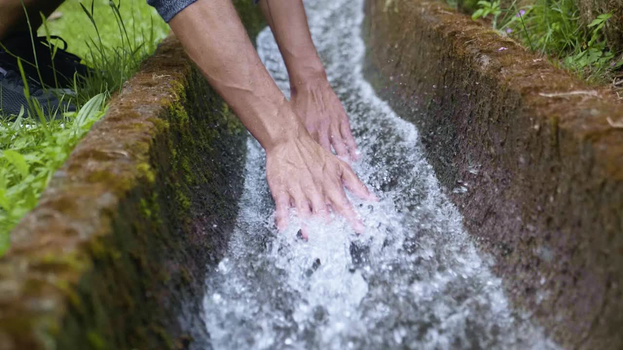 un hombre disfrutando de la sensación del agua fresca y refrescante con las manos en madeira, portugal - cámara lenta