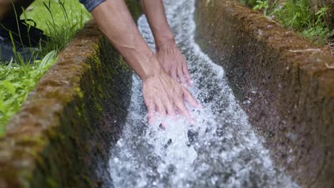 A-man-enjoying-the-feel-of-the-cool,-refreshing-water-with-his-hands-in-Madeira,-Portugal---Slow-motion