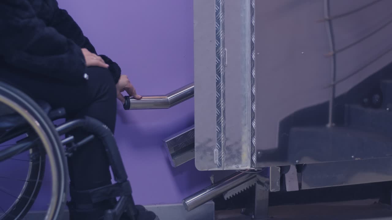 체어에 앉은 장애인 여성이 기계 엘리베이터로 계단을 올라갑니다.