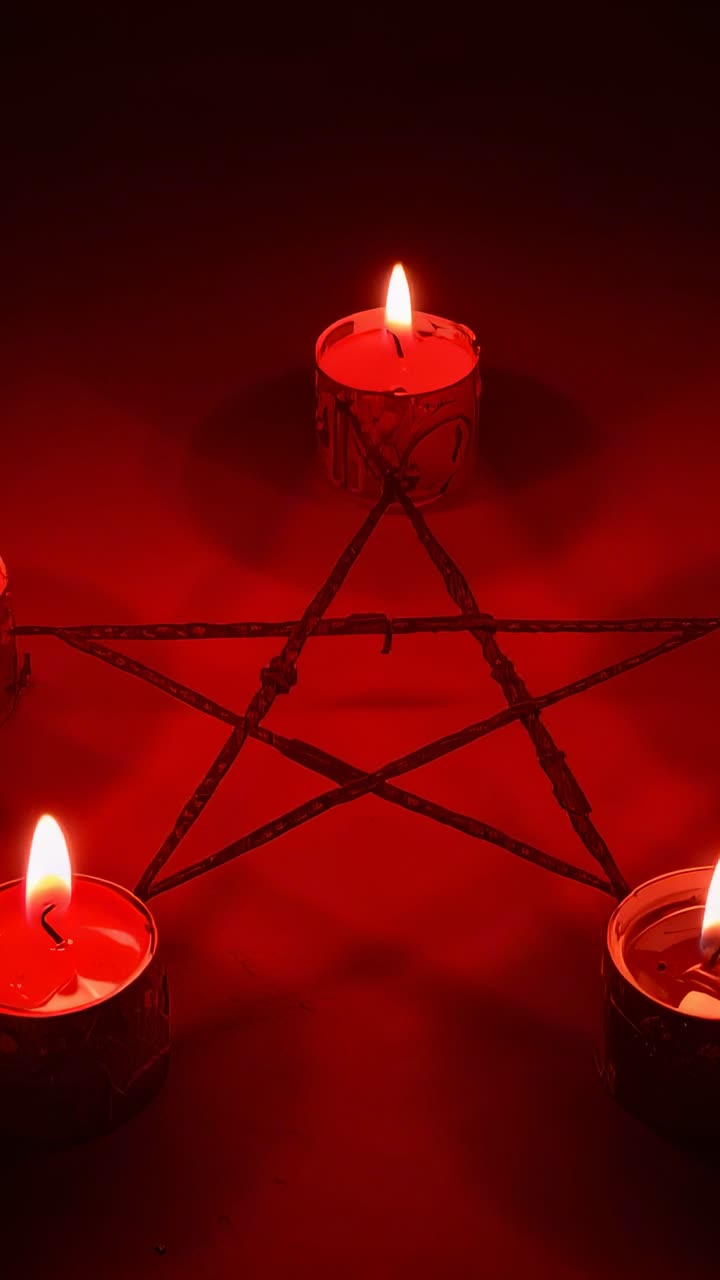 Vertical video: Opening capturing flickering red flames on pentagram sticks creating ritual glow