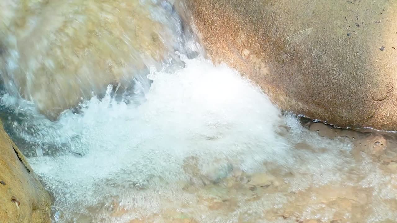 A detailed view of water cascading over smooth rocks, highlighting the dynamic motion and texture.