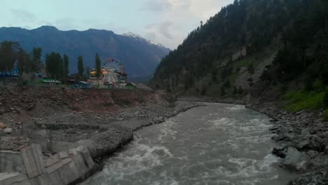 aerial over swat river with ferris wheel in background in kalam, pakistan