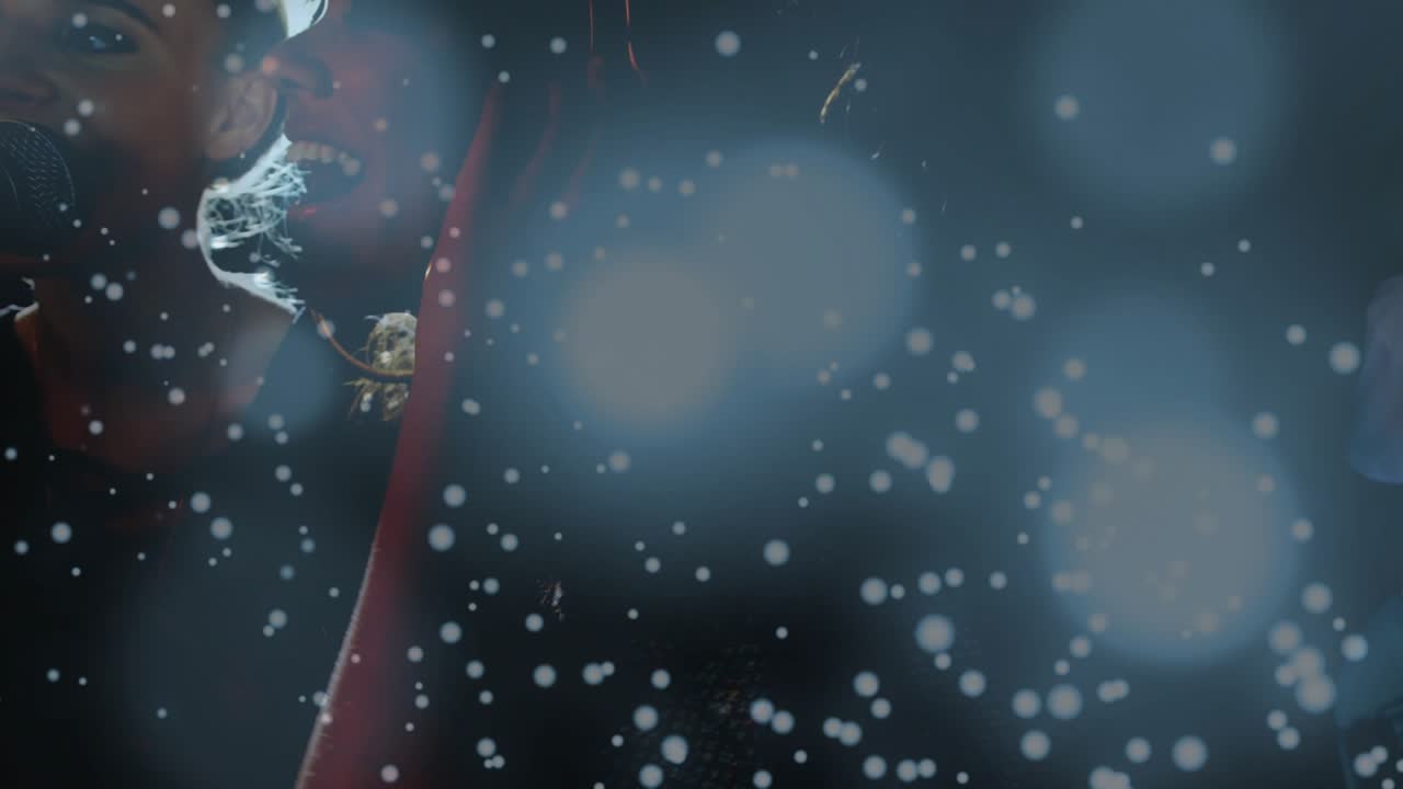 Music duo tuning headphones and leaning into mic, singing as backlit lens flare and snow swirl