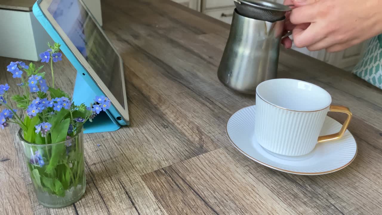 여자 손 이 집 안 의 접시 를 가진  컵 에 카이즈베 에서 커피 를 고 있다