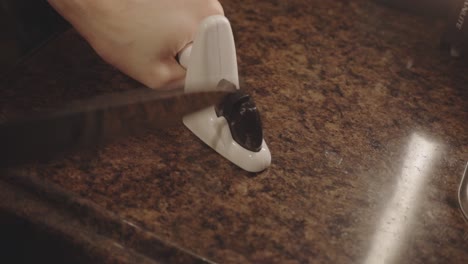 man's hand sharpening a kitchen knife using a manual knife sharpener