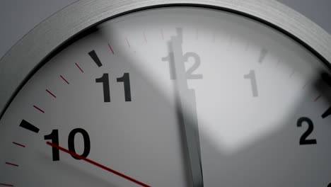 close up of a white ticking clock on white background, pointing midnight, window reflection