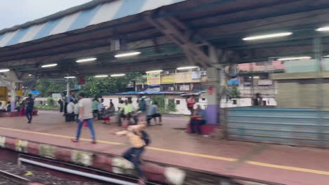 mumbai suburban local train passes by revealing dombivli station with people crossing tracks
